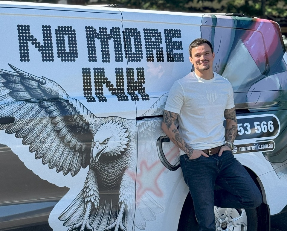 A man standing beside the No More Ink mobile treatment van